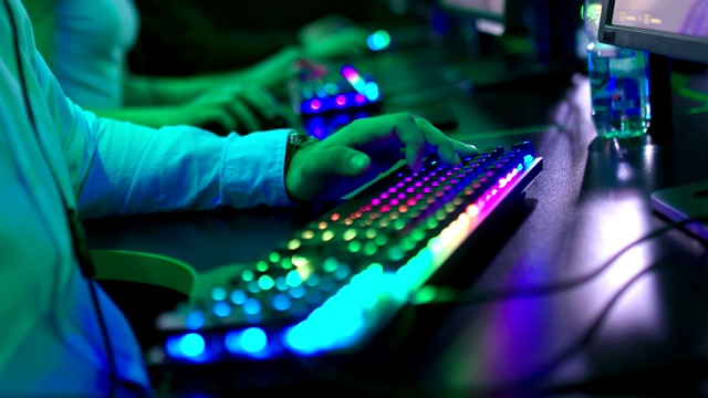 男人坐在电脑前，用手指按键盘上的按钮。背光键盘。特写镜头。视频素材