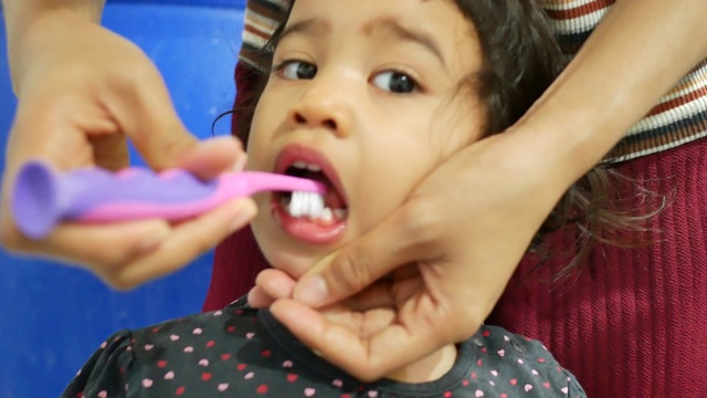 亚洲母亲在浴室里给她的学龄前可爱的小女孩刷牙视频素材