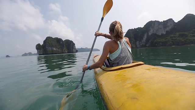 女人在平静的海面上划桨，地平线上有岛屿视频素材