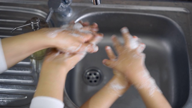 母亲教儿子在厨房洗手视频素材