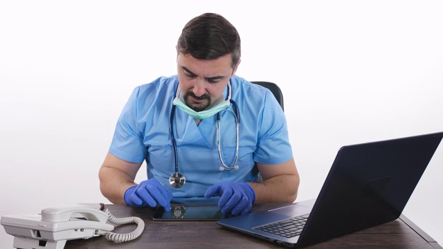 男医生戴着听诊器和蓝色手术手套在平板电脑上打字，移动摄影视频下载