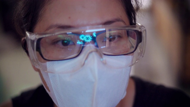 亚洲女医生戴着口罩和护目镜看电脑上的冠状病毒数据图像。视频下载