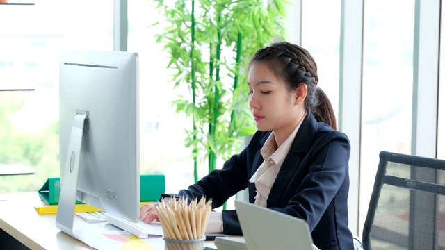 年轻的亚洲女性早上在办公室独自敲击键盘。商业女性工作在电脑和输入数据到系统视频素材