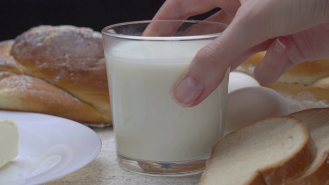 女手里拿着一杯牛奶，上面放着烘焙产品，黄油，鸡蛋，。早餐。奶制品。视频下载