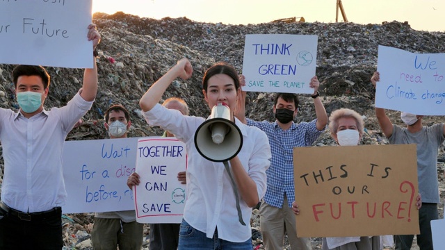 在亚洲的一个巨大的垃圾填埋场上，亚洲领袖女性用扩音器高喊，她们举着环保运动活动家为自然而战的海报。志愿服务、慈善、清洁、生态视频下载