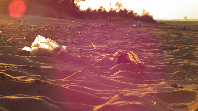 在日落时用镜头光晕慢动作在沙滩上捡垃圾视频素材