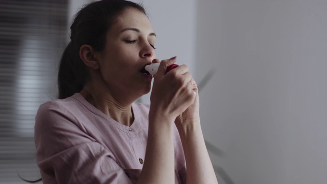 年轻女子在家用录像带里使用哮喘吸入器视频下载
