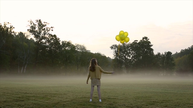 清晨，女孩在田野里放飞黄色气球视频下载