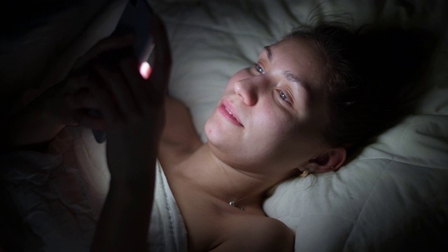 躺在床上用手机浏览社交网络的女孩视频下载