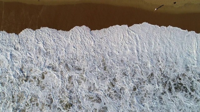 海洋冲浪波。泡沫状的海浪翻滚着涌向沙滩。视频素材