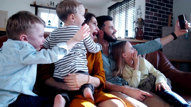 幸福年轻的白种人家庭与三个孩子聊天，招手通过智能手机视频电话在家里的朋友慢动作。视频素材