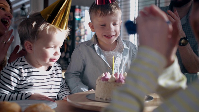 可爱快乐的小白种人男孩许愿，吹生日蛋糕在有趣的庆祝与家庭慢动作。视频下载