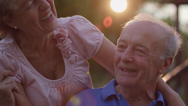 微笑的老年妇女拥抱她的爱的丈夫，而他们在户外放松视频素材