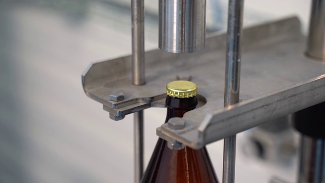 在啤酒装瓶生产线上自动盖上瓶盖。视频素材