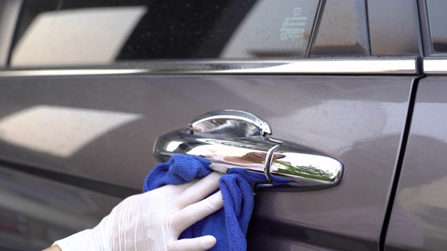 “女人的手”在家里擦拭清洁covid-19病毒的灰色汽车门把手表面。视频素材