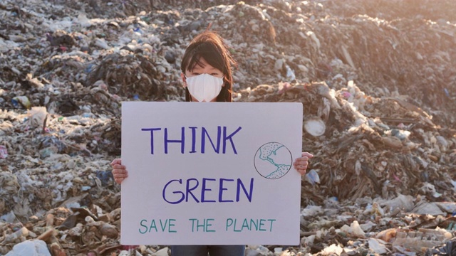 描绘一个年轻的亚洲小女孩站在一个巨大的垃圾堆上，从亚洲的垃圾填埋场拿着为环保运动积极分子争取自然的海报。志愿服务，慈善，清洁，人，儿童，生态概念，儿童关于可持续发展视频素材