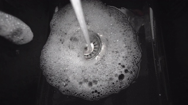 水从打开的水龙头流入黑色花岗岩水槽，特写视频素材
