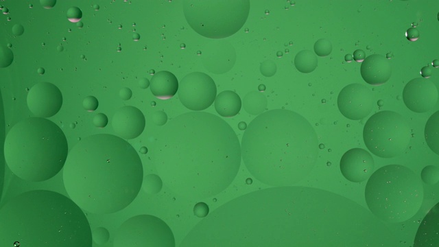绿色的油球浮在水面上。液体顺时针循环运动，气泡微距拍摄。抽象的智能手机主屏幕风格，主题或背景，翠绿色，世界环境视频素材