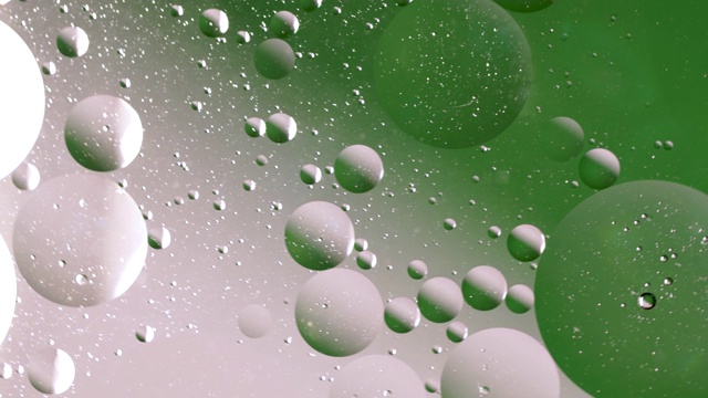近距离观察水中的白色和绿色气泡。圆形气泡在液体中的循环运动，气泡微距拍摄。抽象的主屏幕风格，主题或背景，翠绿色闪亮透明视频素材