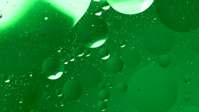 近距离观察绿色油在水中的气泡。圆形气泡在液体中的循环运动，气泡微距拍摄。抽象的智能手机主屏幕风格，主题或背景，翠绿色闪亮，视频素材