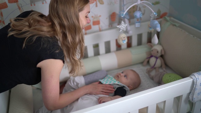 母亲和刚出生的男婴在婴儿床上玩得很开心视频下载