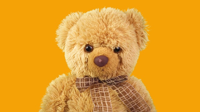橙色背景上的泰迪熊。儿童玩具在运动。最喜欢的玩具视频下载