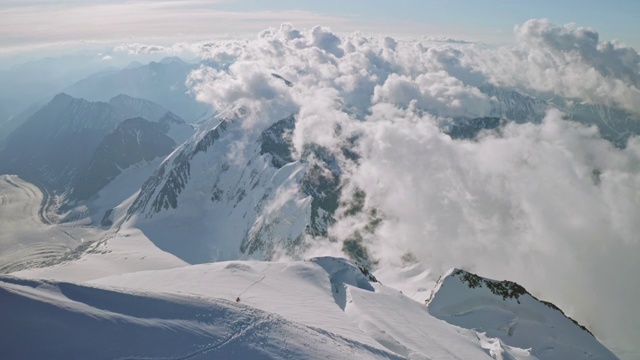 雪峰下飘着史诗般的魔法云，攀登者登临山顶视频素材