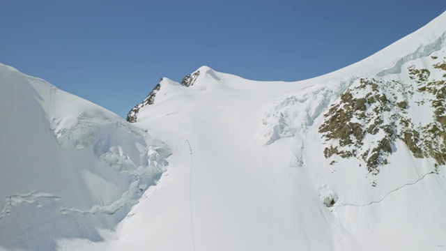 美丽的阳光山，登山运动员爬上巨大的斜坡与积雪视频素材