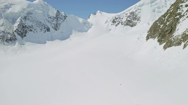 鸟瞰全景，登山运动员在广阔的雪原上移动，登上山顶视频素材