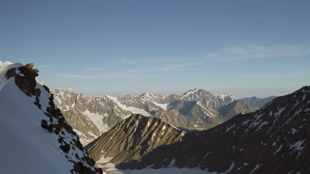 高地全景，雪峰边缘，登山者攀登陡峭的山坡视频素材