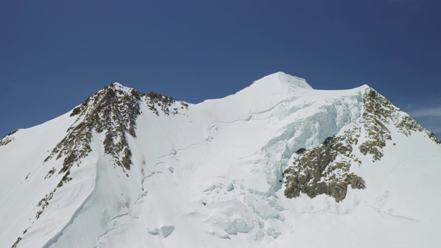 高空全景，耀眼的雪山峰顶高耸于湛蓝的天空视频素材