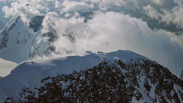 鸟瞰绝美，攀登者在雪山之巅，云雾缭绕峰顶视频素材