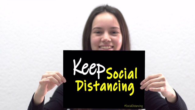 保持社交距离的信息概念。青少年拿着写在黑板上的社交距离标志。视频下载