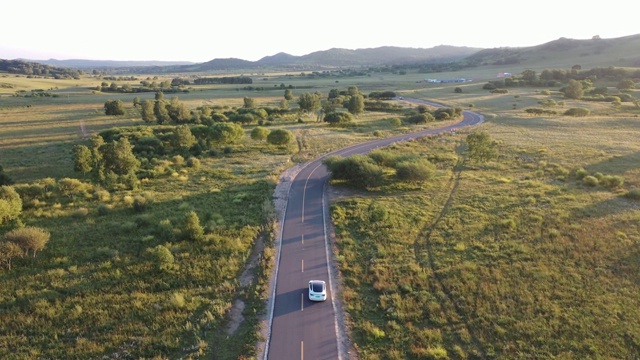 4K交通鸟瞰图白色汽车行驶在乡村道路上视频下载
