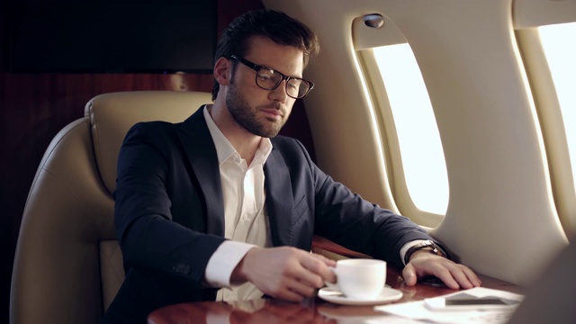 自信的商人在飞机上喝咖啡视频下载