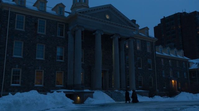 学院或大学建筑的广角。标牌上写着“国王学院大学”。人们进入大楼。雪可见。柱子或列。视频素材