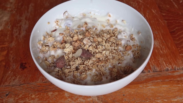 将燕麦片倒入一碗酸奶中视频素材