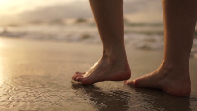 美丽的场景，一个低段的女人走在海边的日落视频下载