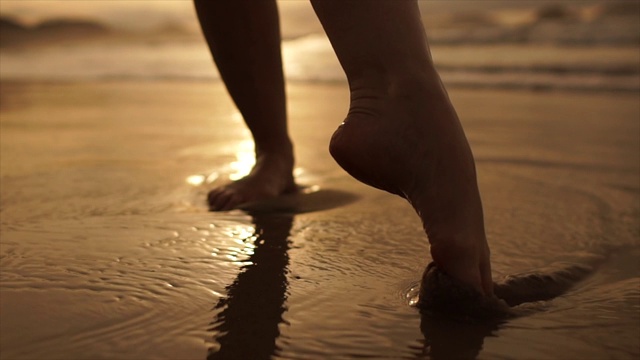 美丽的场景，一个低段的女人走在海边的日落视频素材