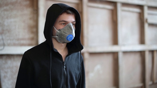 一个戴着呼吸器和兜帽的年轻人站在废弃的建筑里视频素材