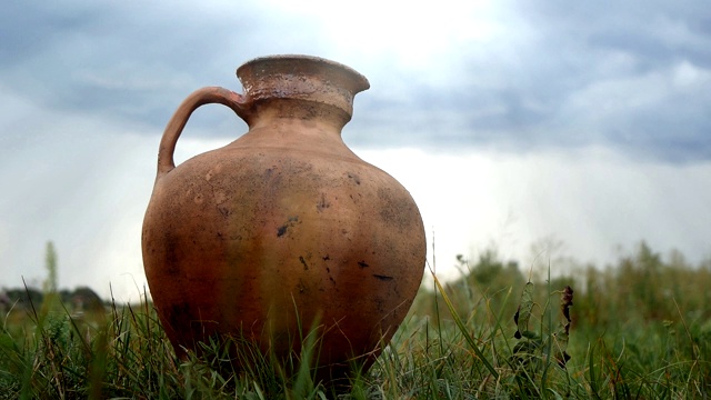古老的大陶罐站在草地上，以天空为背景视频下载
