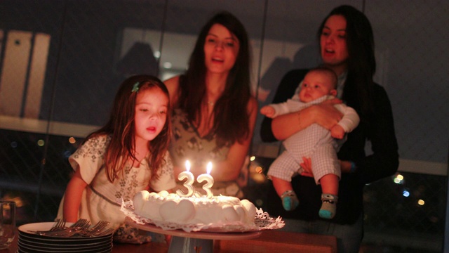 正宗的生日庆祝，家庭成员唱生日歌，吹蜡烛在蛋糕上视频素材