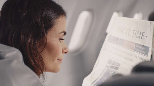 女商人在商务飞机上看报纸视频素材