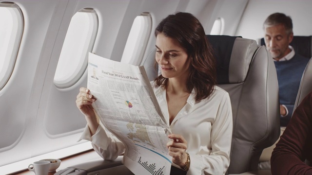 女专业人士在飞机上看报纸视频素材
