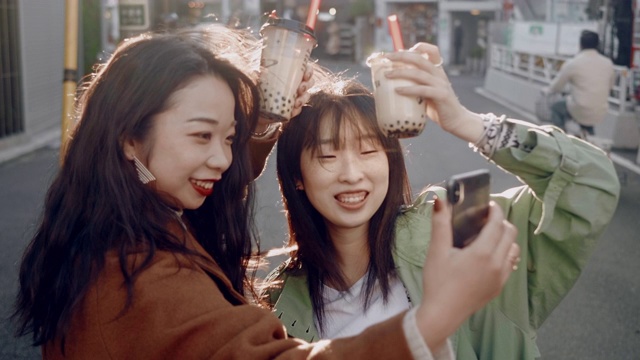 时尚的日本女性朋友在夕阳下与珍珠奶茶自拍视频素材