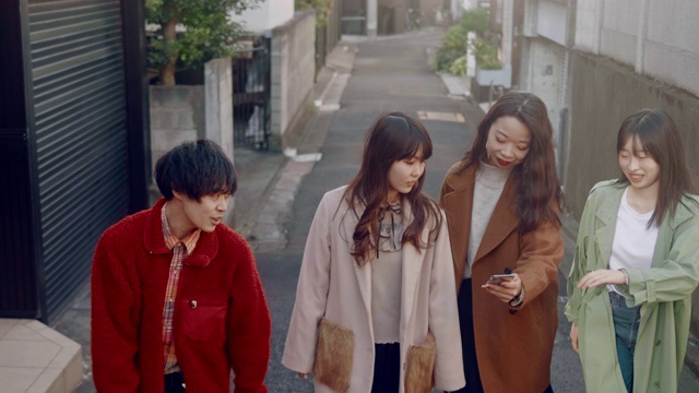 一群时髦的日本年轻人在原宿边走边玩智能手机视频素材