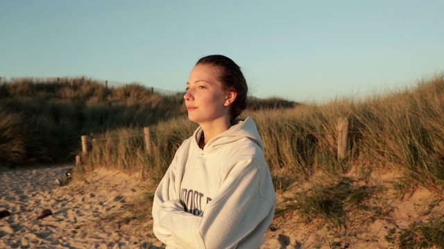 年轻女子呼吸着空气，看着海滩上的日落，在一个平静的时刻视频下载