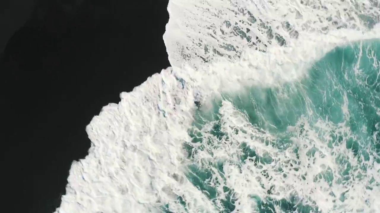 航拍旋转的波浪上滚到一个黑色的沙滩，兰萨罗特，西班牙视频素材