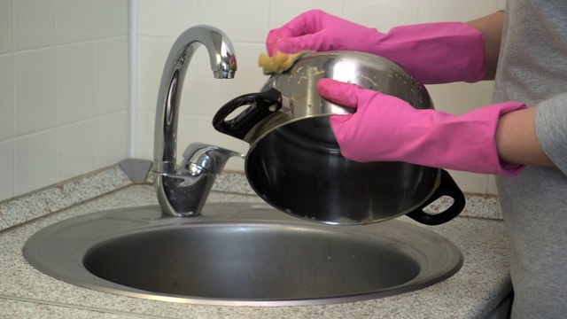 一位戴着橡胶手套的妇女用海绵清洗金属罐的油脂。视频素材
