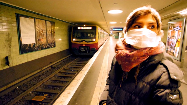 一个戴着面具的年轻女子在空无一人的地铁站里等待视频素材